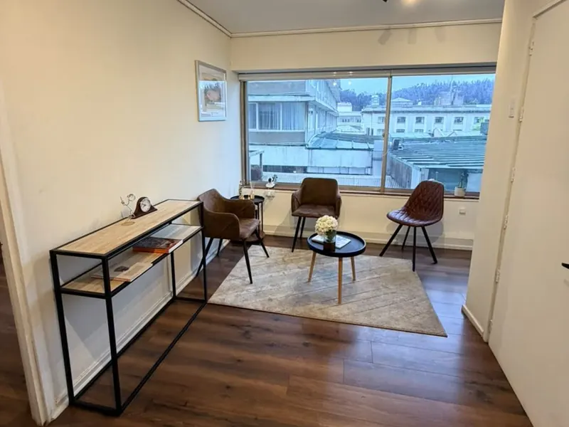 Sillones y mesa de centro junto a la ventana de la oficina 409, con vista a la ciudad